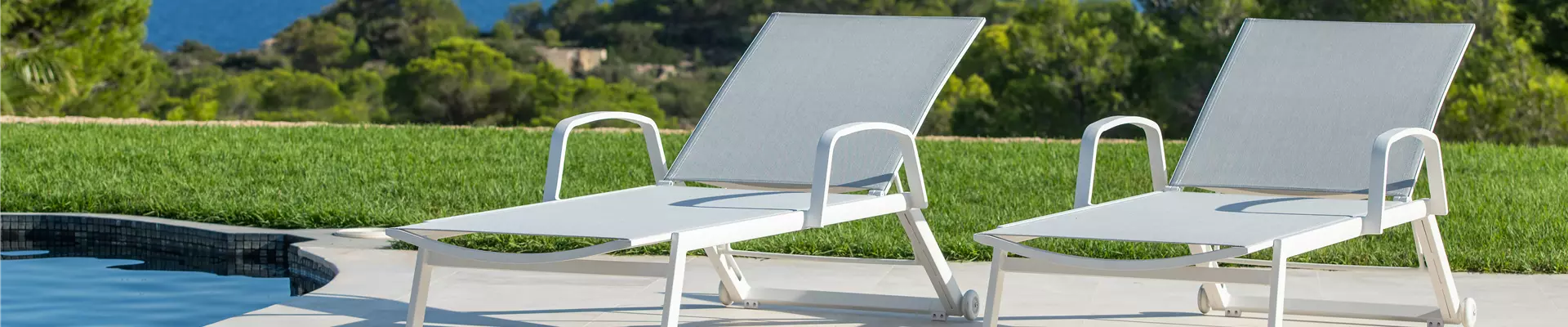 Zwei helle Sonnenliegen nebeneinander an einem Pool